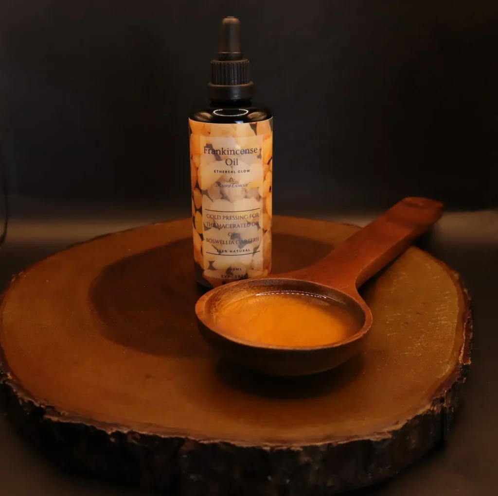 Product shot with black background for the bottle of frankincense oil with a wooden spoon full of the oil BY azara natural