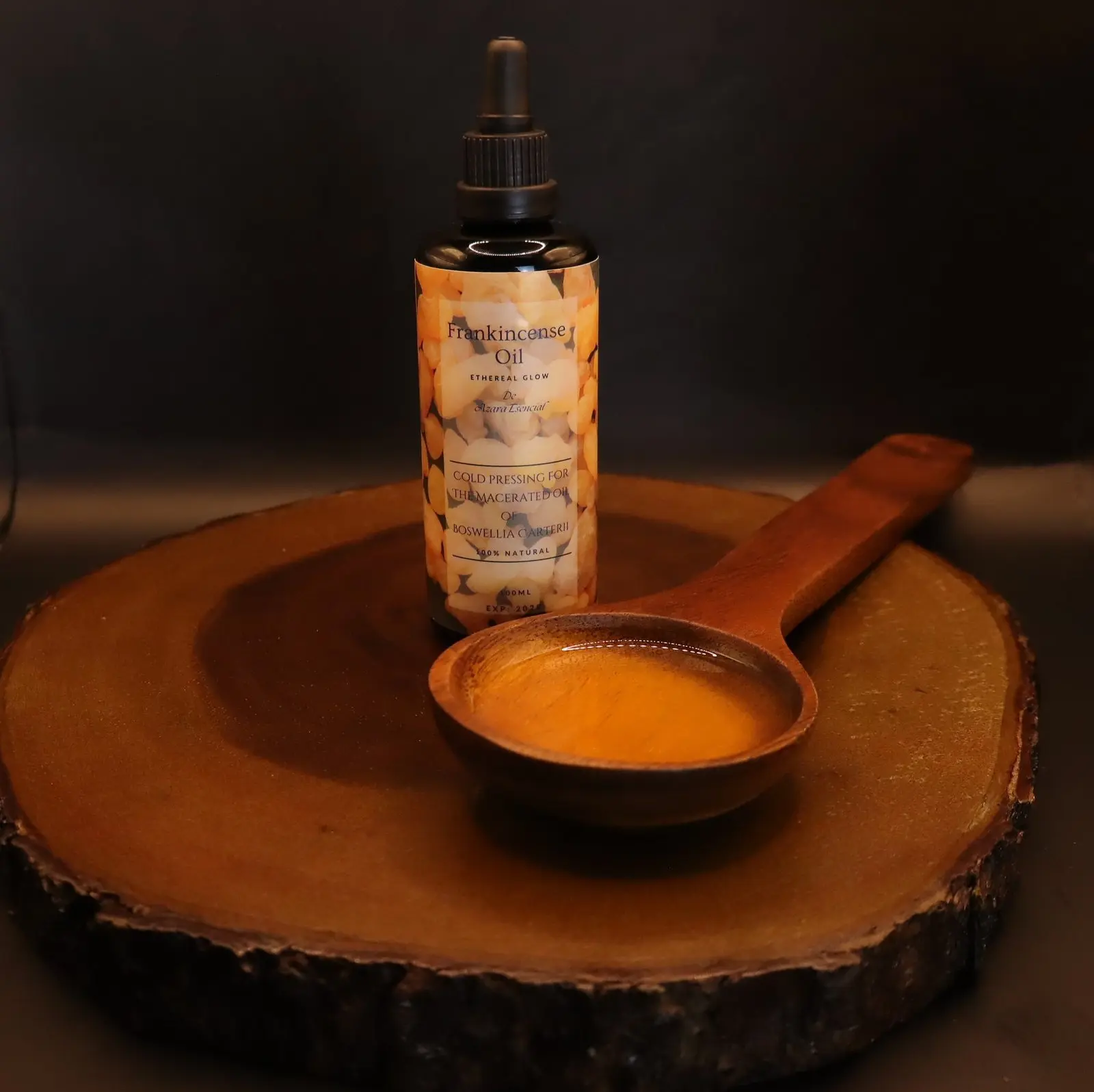 Product shot with black background for the bottle of frankincense oil with a wooden spoon full of the oil BY azara natural
