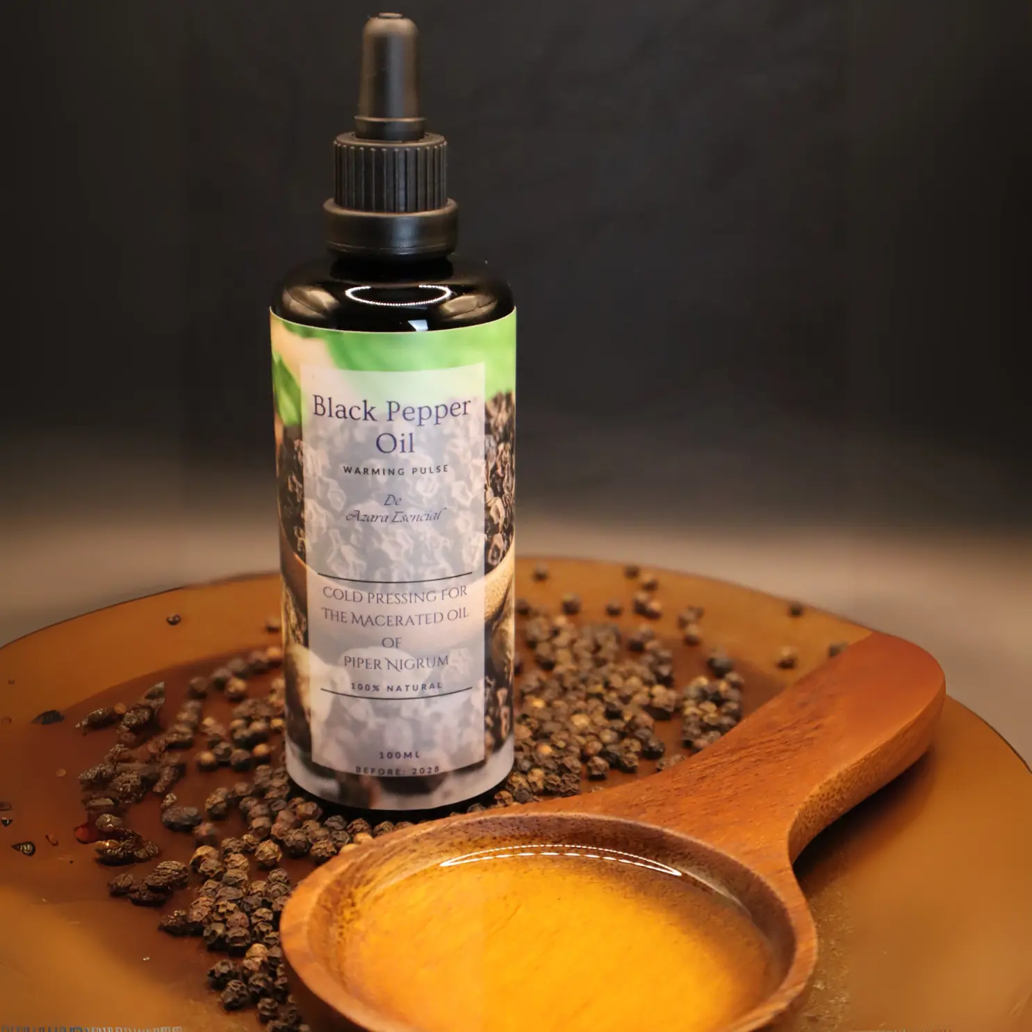 products shot for bottles of oils of black pepper oil natural black pepper grains ingredients and wooden spoon full of the oil with black background and wooden base BY azara natural