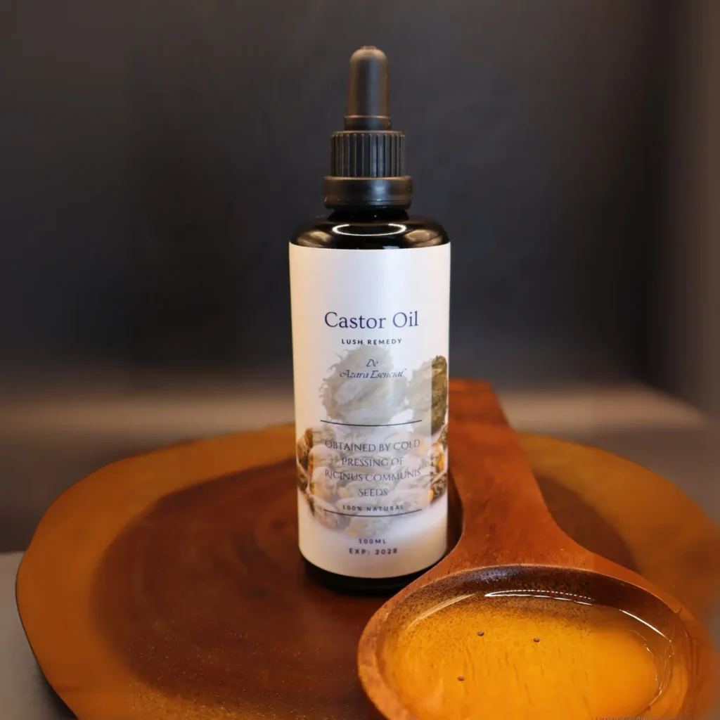 Product shot with black background for the bottle of castor oil with a wooden spoon full of the oil BY azara natural