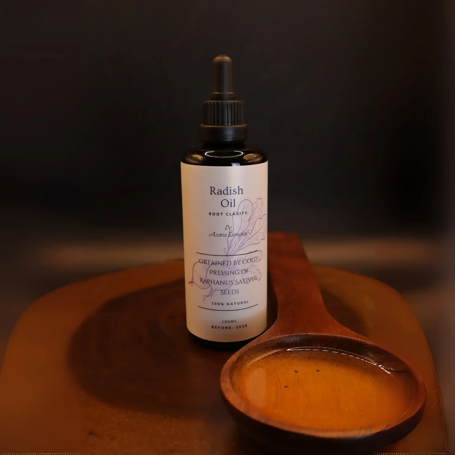 Product shot with black background for the bottle of radish oil with a wooden spoon full of the oil BY azara natural