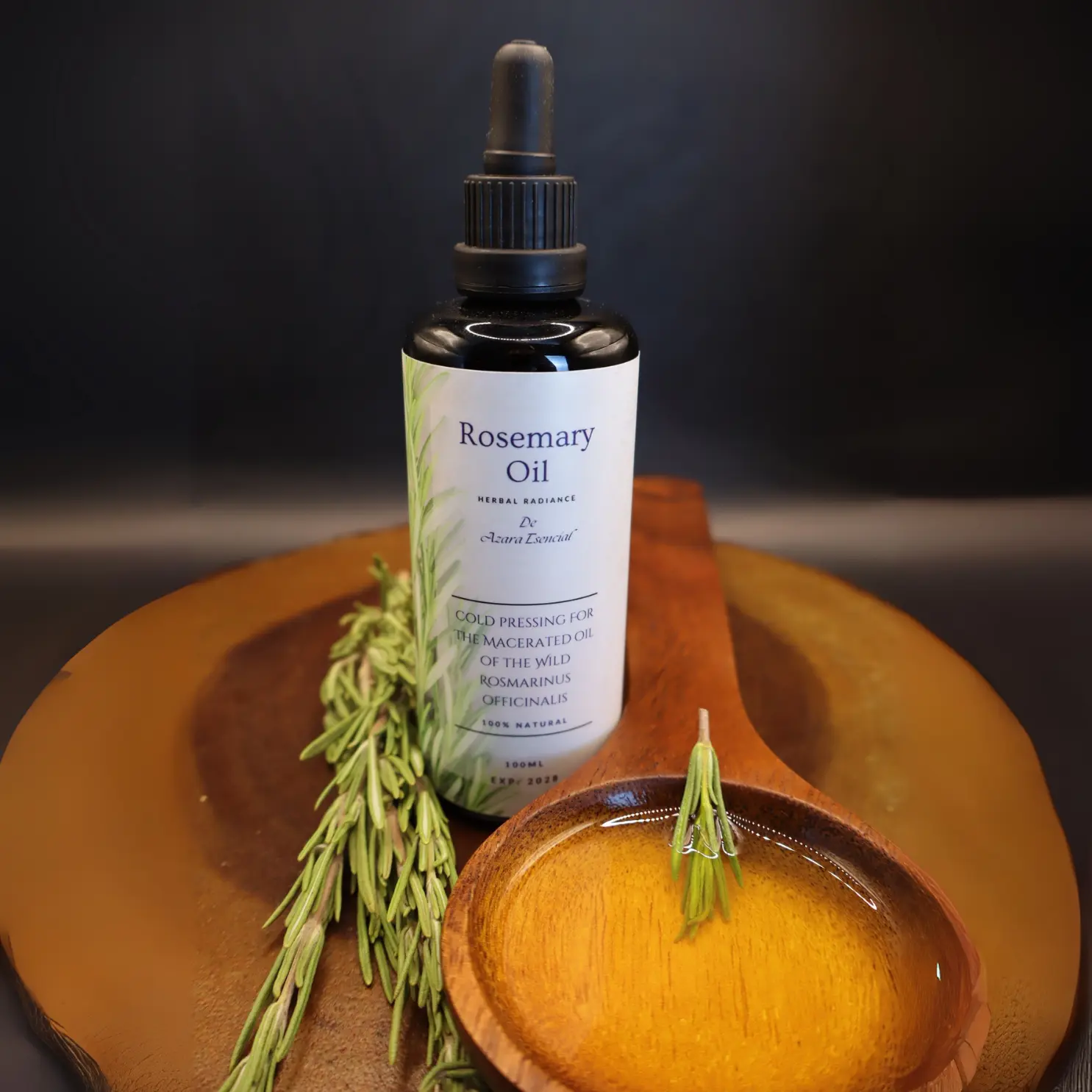 macerated-then-cold-pressed-rosemary-oil-product shot with black background and a spoon of wood full of the oil with With a sprig of rosemary. BY azara natural